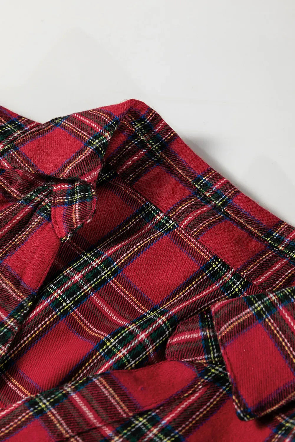 Red plaid mini dress with a shirt collar, long sleeves, half-button front, and a ruffle hem.