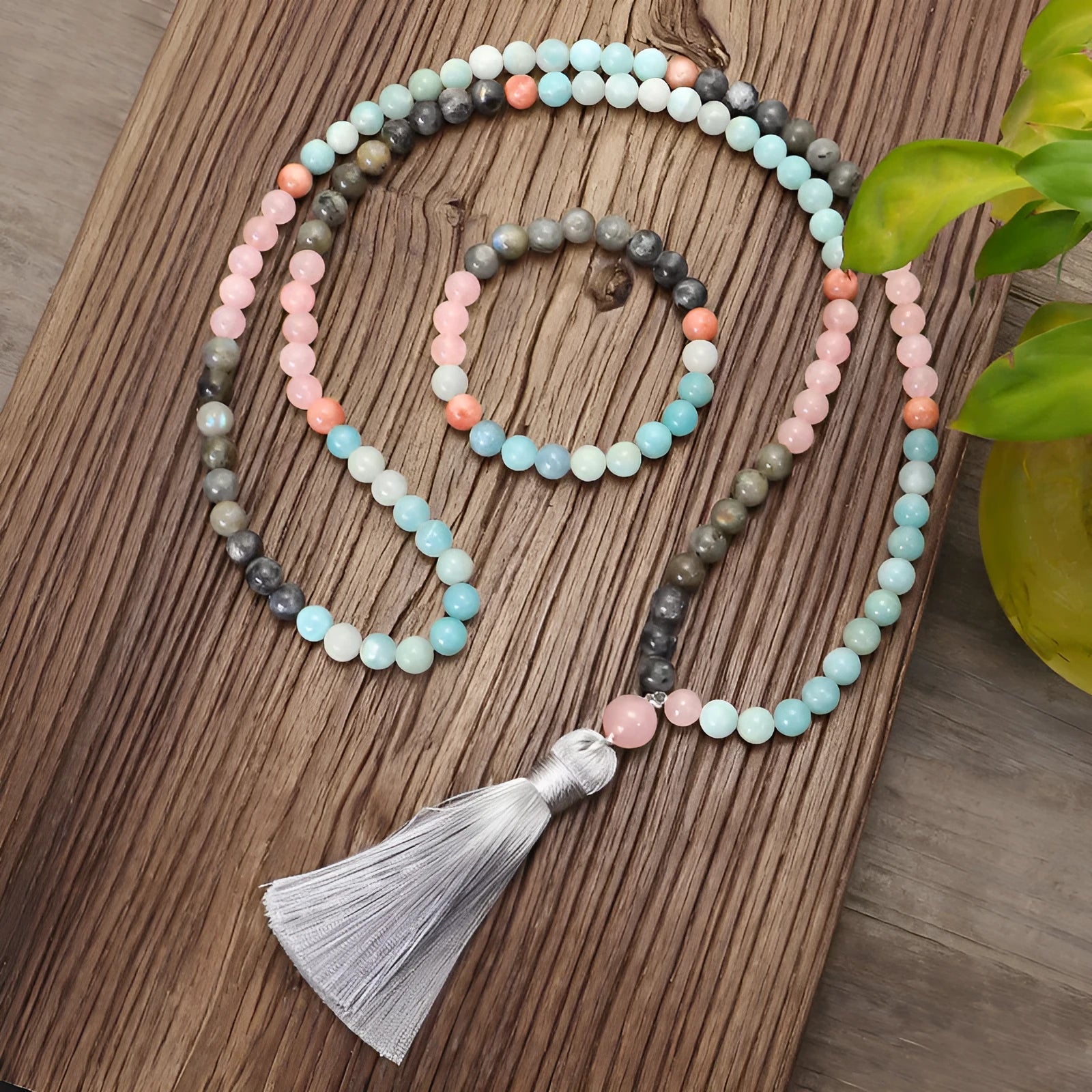 Bohemian style necklace and bracelet set with colourful drop-shaped stone pendants and tassel details on a white background