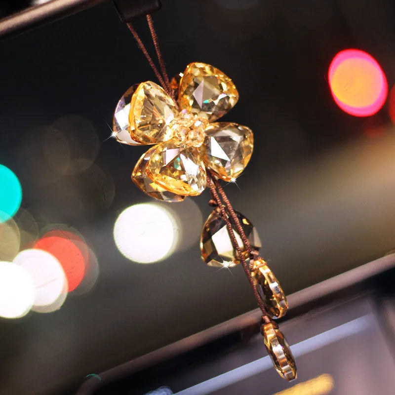 Crystal four leaf clover car pendant hanging, shown in one of four colour options: transparent, champagne, translucent black, or extremely shiny.