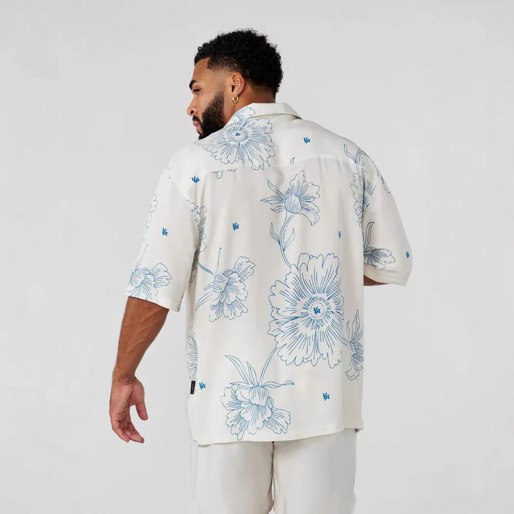 Man wearing a loose-fitting, short-sleeved printed top with a floral pattern in a neutral colour