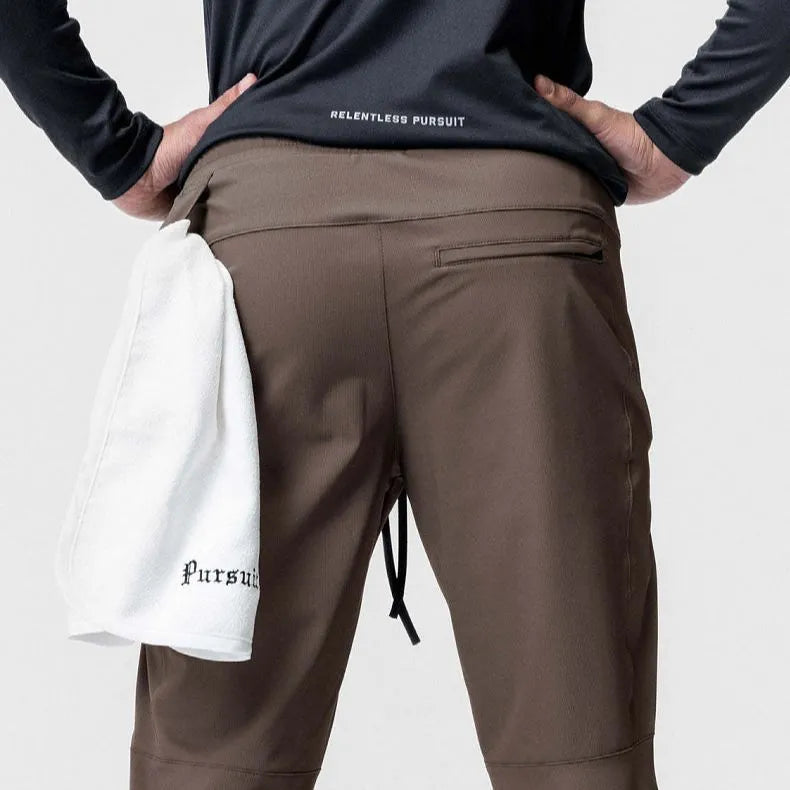 Man wearing dark grey loose-fit ankle-tied fitness trousers made of quick-drying polyester during a workout.