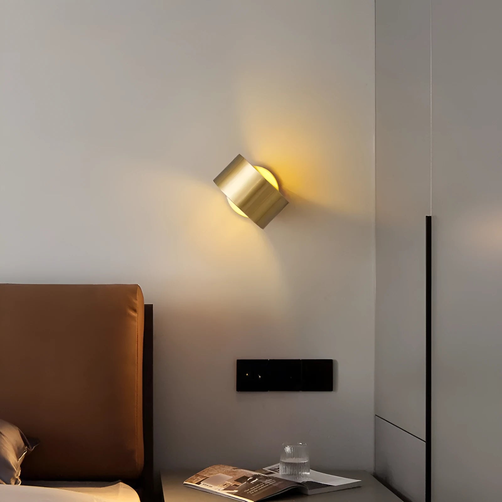 A simple modern copper wall lamp on a wall, shown in a black finish.