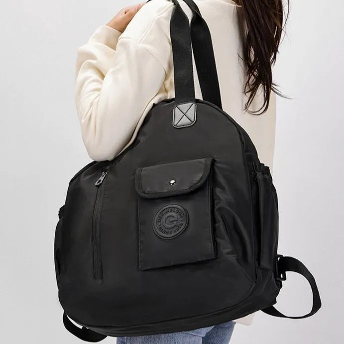 Large black nylon backpack with a front sandwich pocket, shown next to a khaki and a green graphic version.