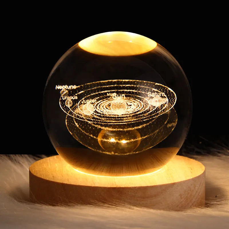 Clear crystal ball LED night light showing a 3D galaxy or planet design, lit from within on a table.