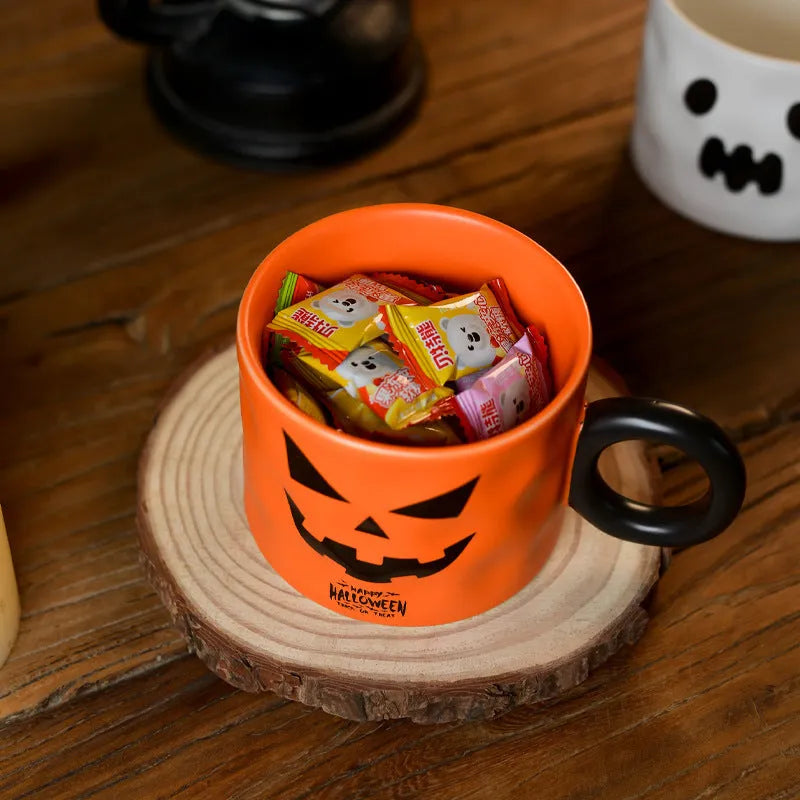 Orange ceramic Halloween pumpkin cup with handle beside dessert spoon in gift box