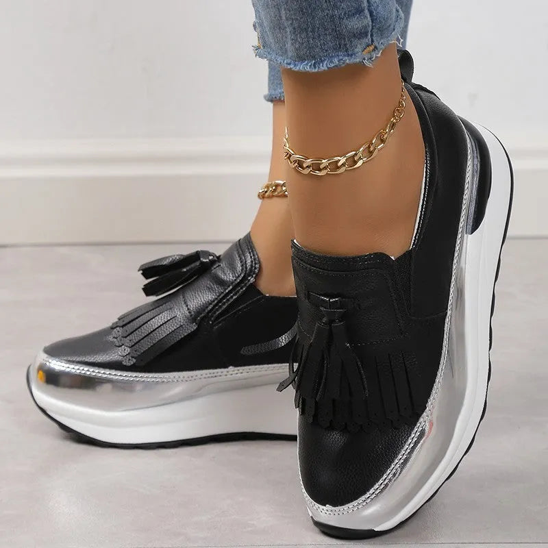 Women's black casual platform shoes with a tassel detail and a distinctive muffin-style wedge heel.