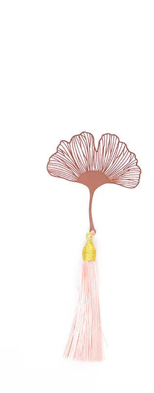 Detailed brass bookmark with hollow maple leaf pendant and rose gold tassel on a book page.