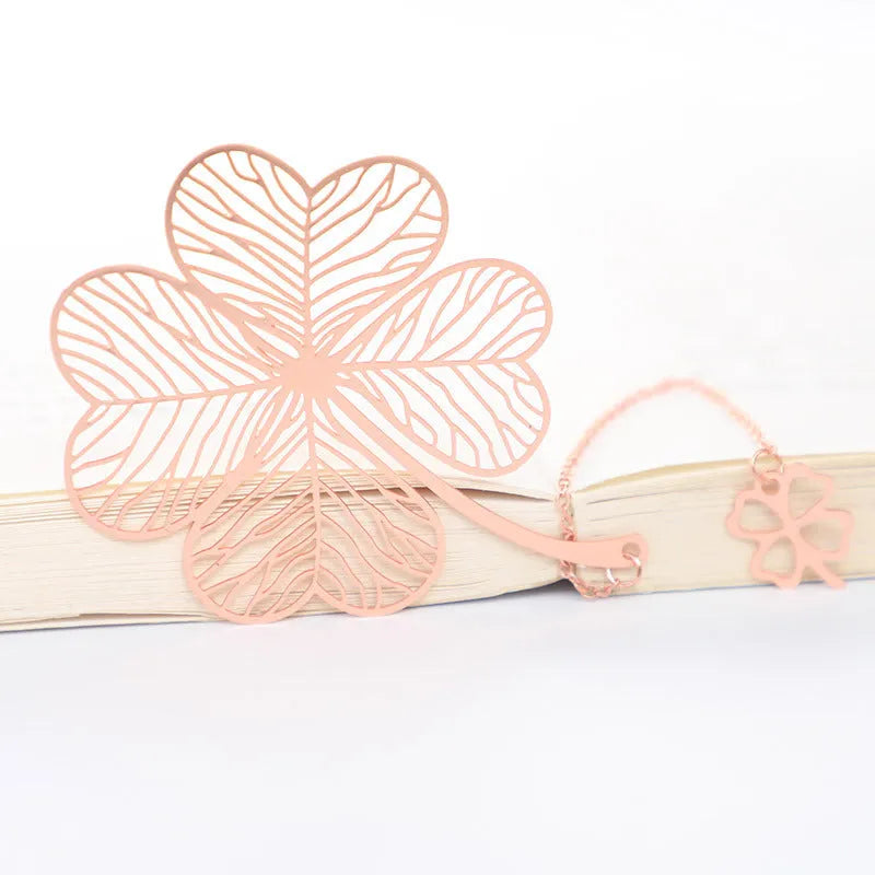 Detailed brass bookmark with hollow maple leaf pendant and rose gold tassel on a book page.
