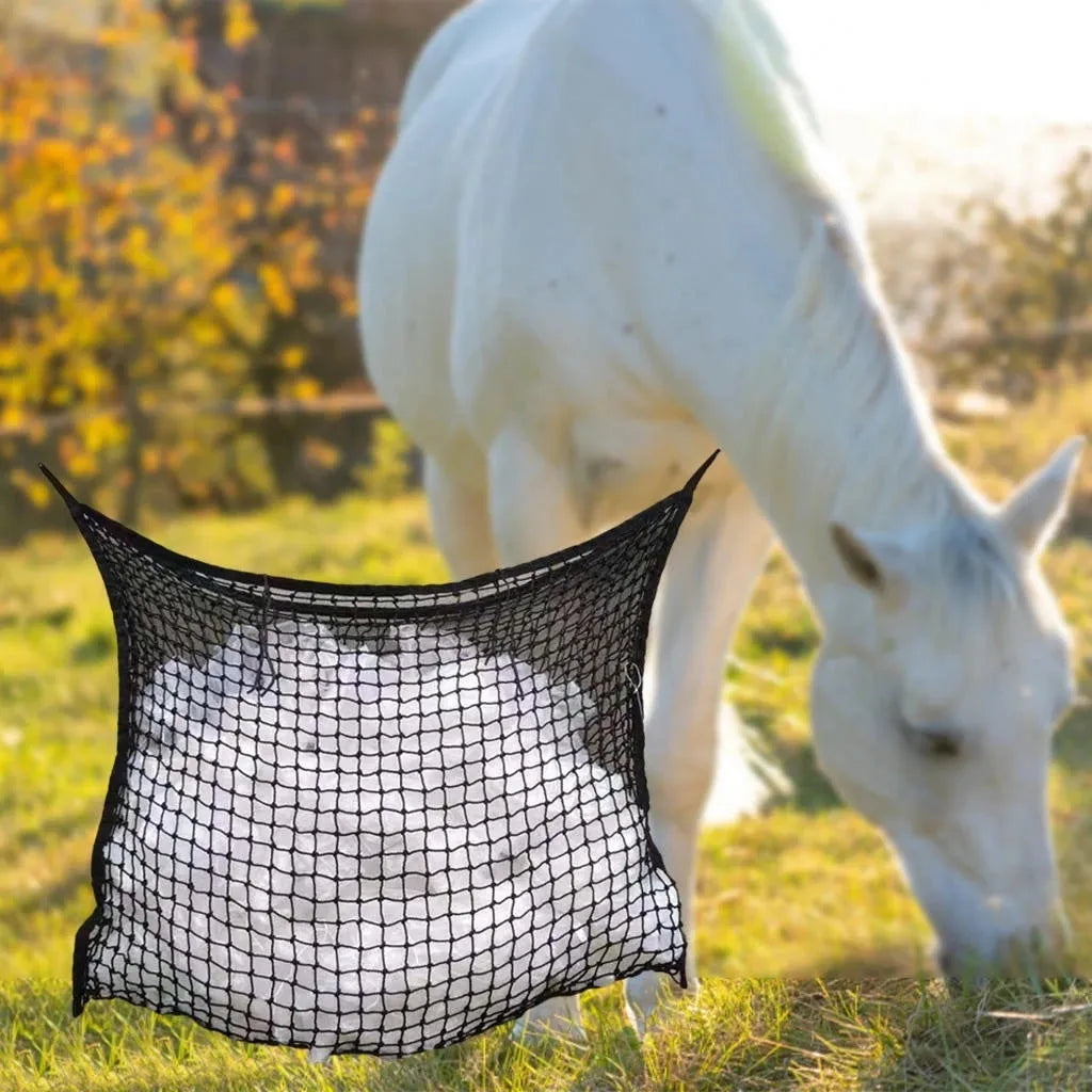 Woven polyethylene rope horse feeding bag in black hanging with hay visible through grid