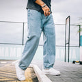 Man wearing dark blue loose straight-leg cotton jeans with a simple design and zipper fly.