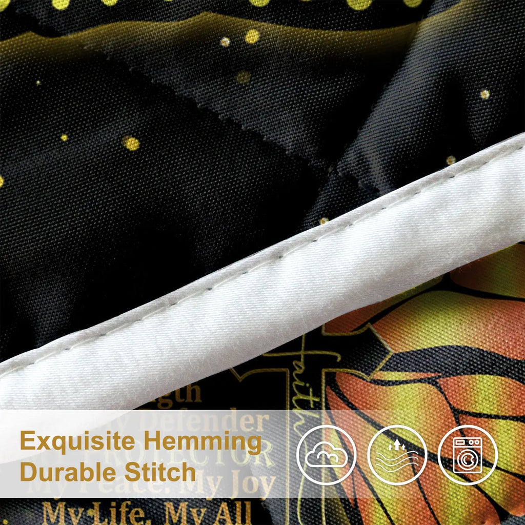 Three-piece black quilt set with butterfly and sunflower pattern, including quilt and two pillow shams, on a bed