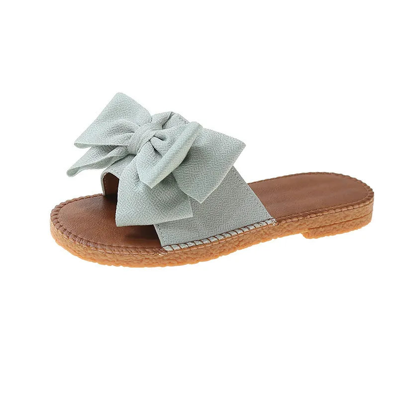 Women's beige slip-on sandals with bow detail and flat rubber sole
