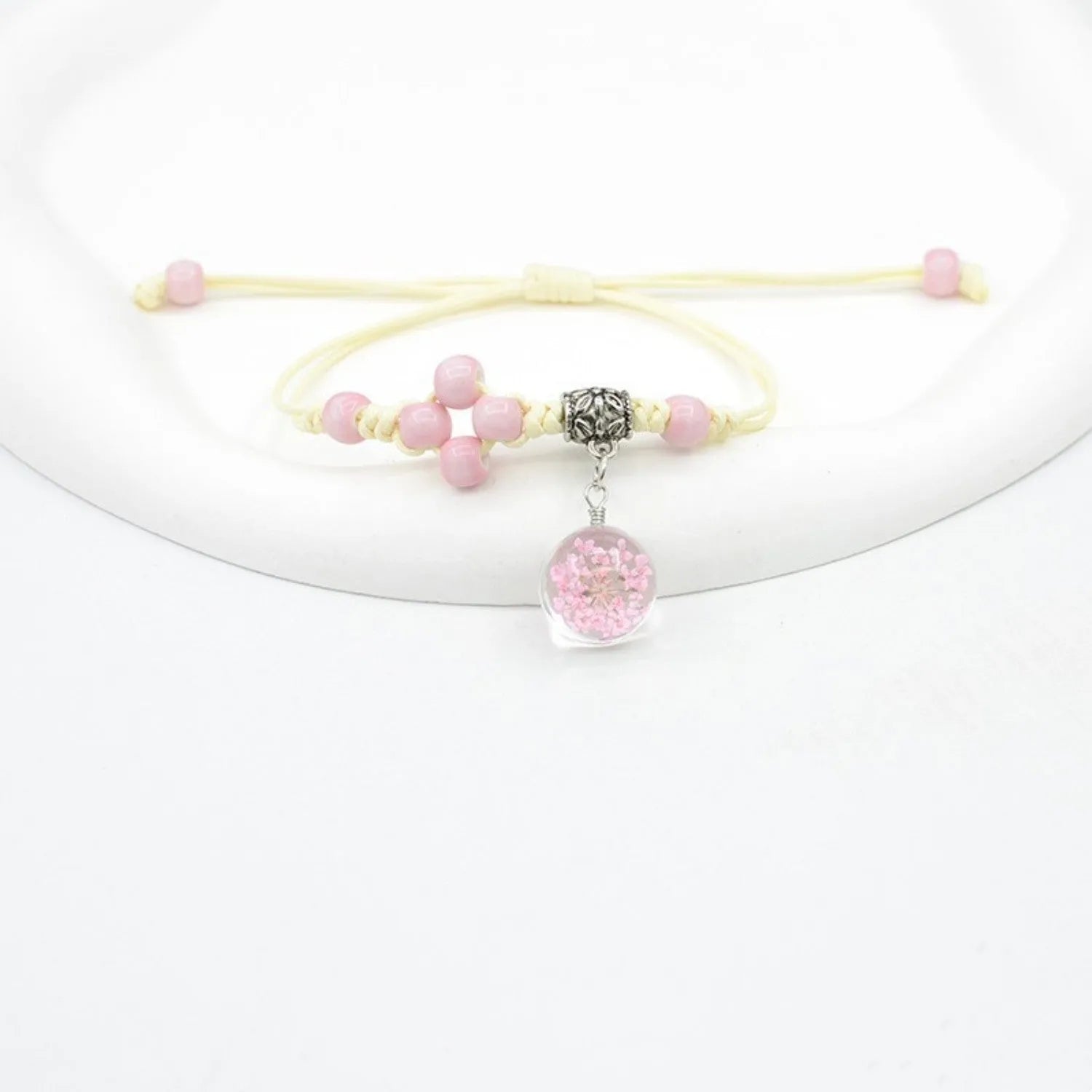 Close-up of a hand-woven glass bracelet with large 1.4cm beads containing real dried flowers and lace floral detailing.