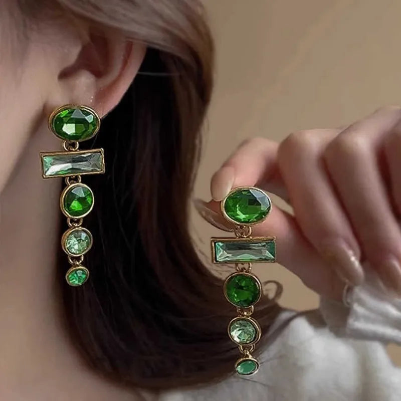 Green gradient geometric alloy earrings with a long tassel and sparkling inlaid zircon centre on a white background.