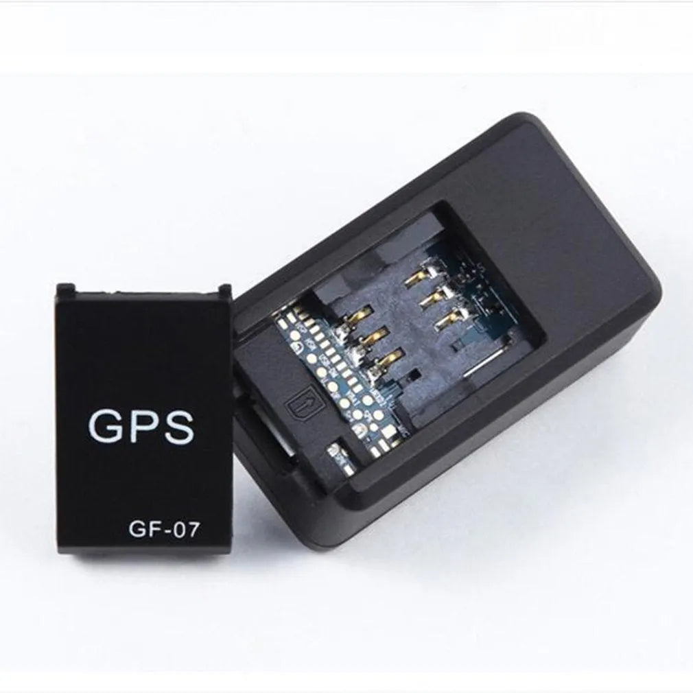 Small black magnetic GPS car tracker with USB charging cable on a metal surface.