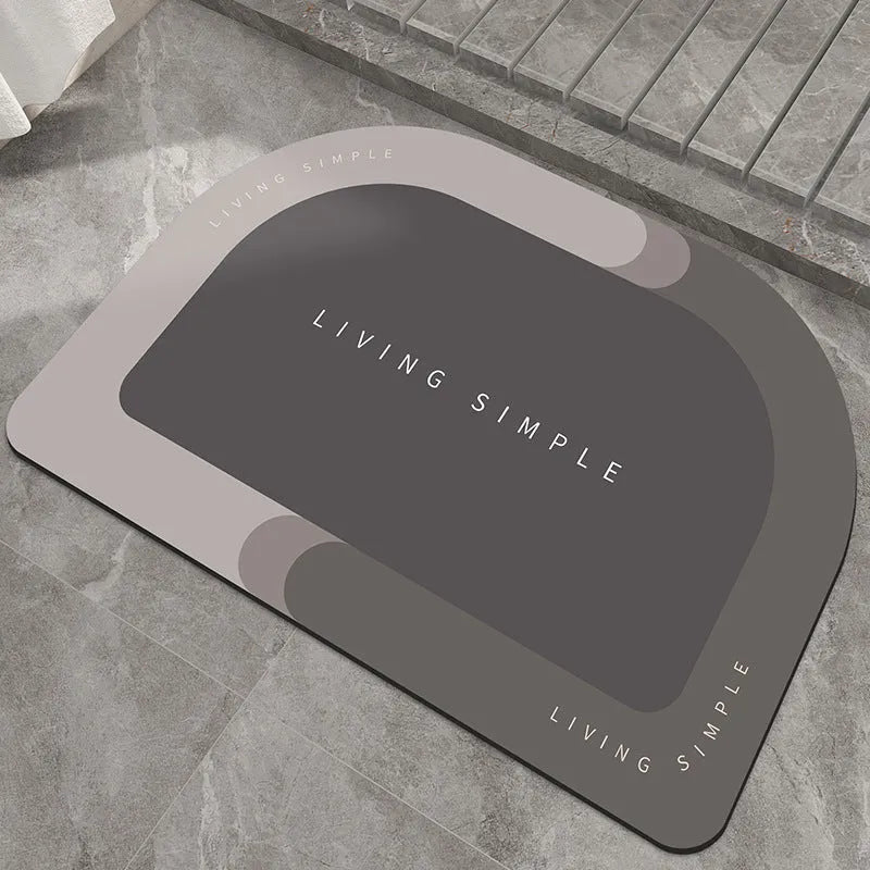 Oval grey polyester door mat with textured rubber non-slip backing on a wooden floor.