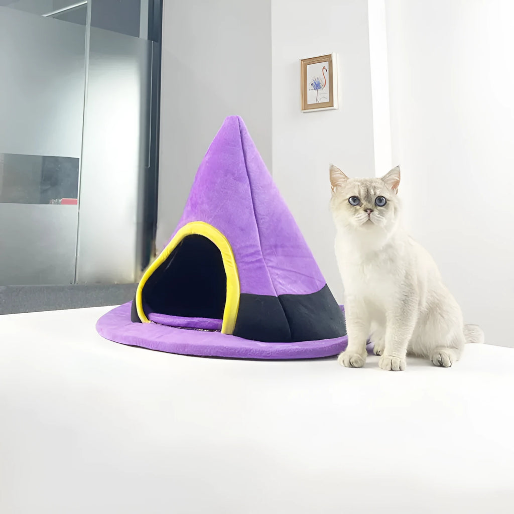 Purple witch hat-shaped cat bed for small pets, shown on a floor.