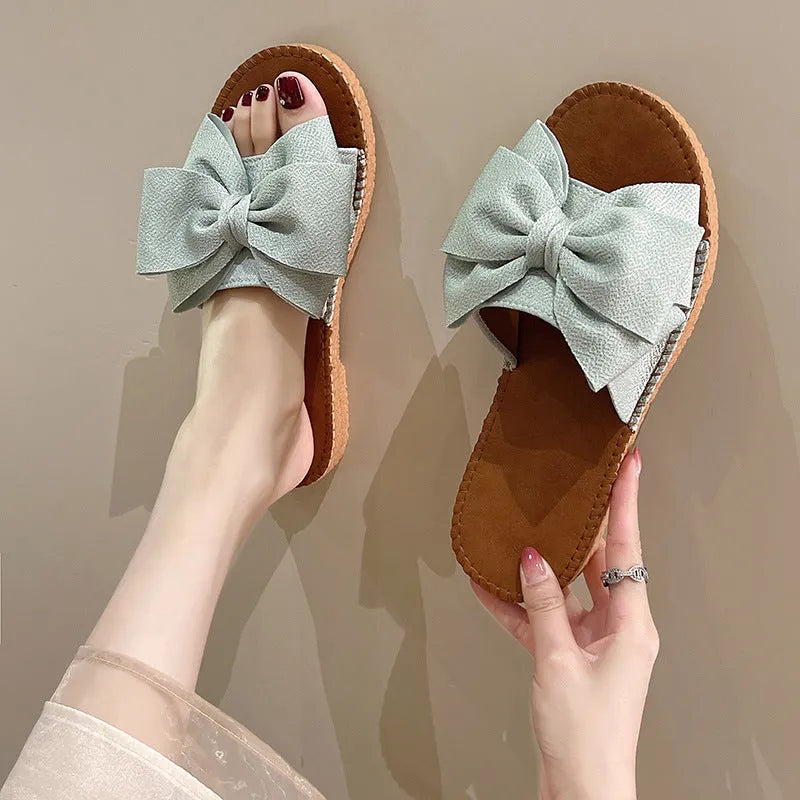 Women's beige slip-on sandals with bow detail and flat rubber sole