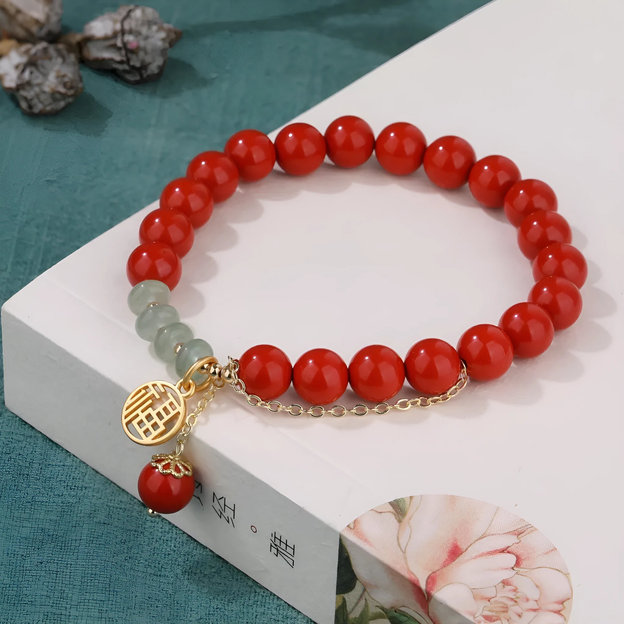 Women's handmade cinnabar bracelet with fu character charm, jade spacer beads, and red sand tassel detail