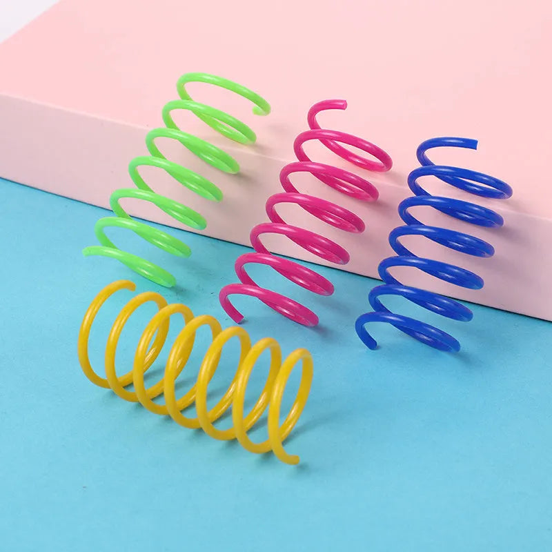 Colourful plastic coil spring toys for cats on a wooden floor.