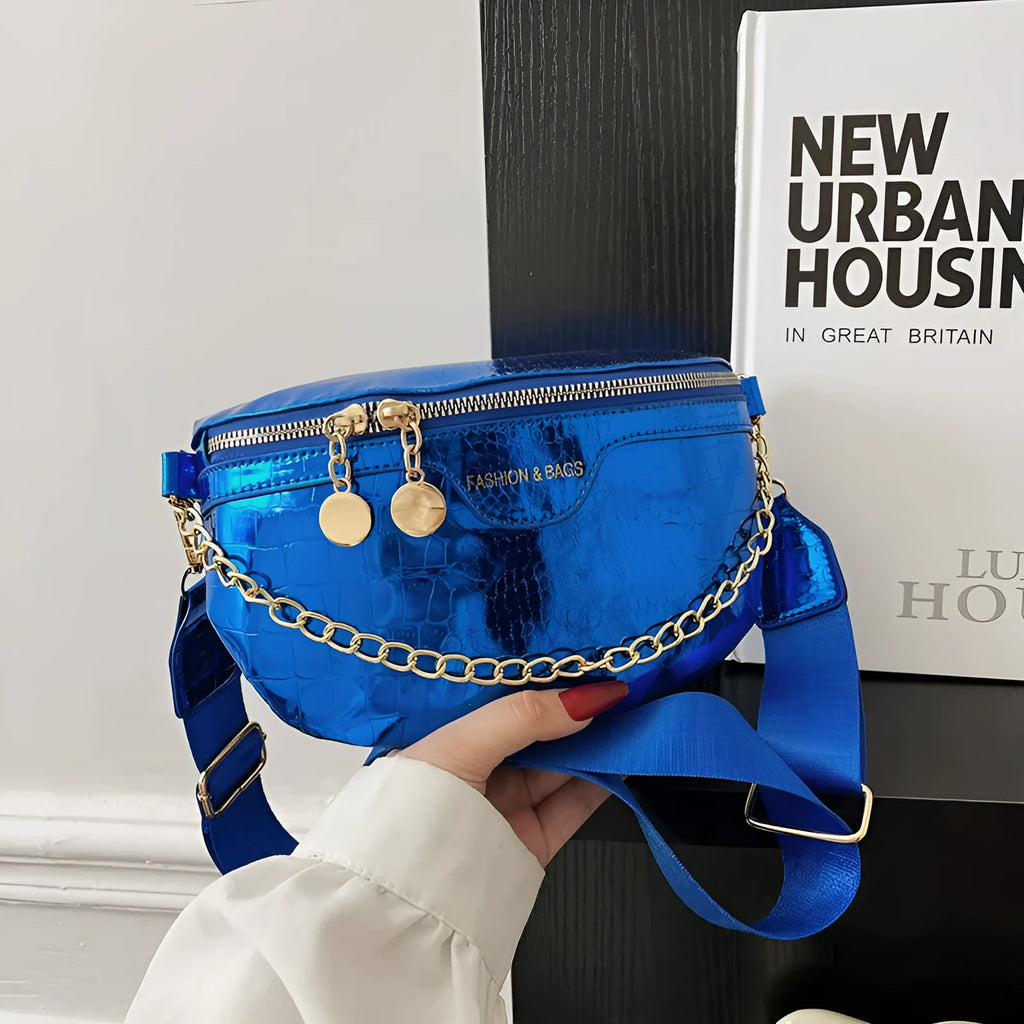 Shiny hard-shell PU chest bag with wide shoulder strap, chain detail, and internal pockets in silver colour