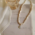 Vintage pearl necklace with geometric alloy pendant on an adjustable chain.