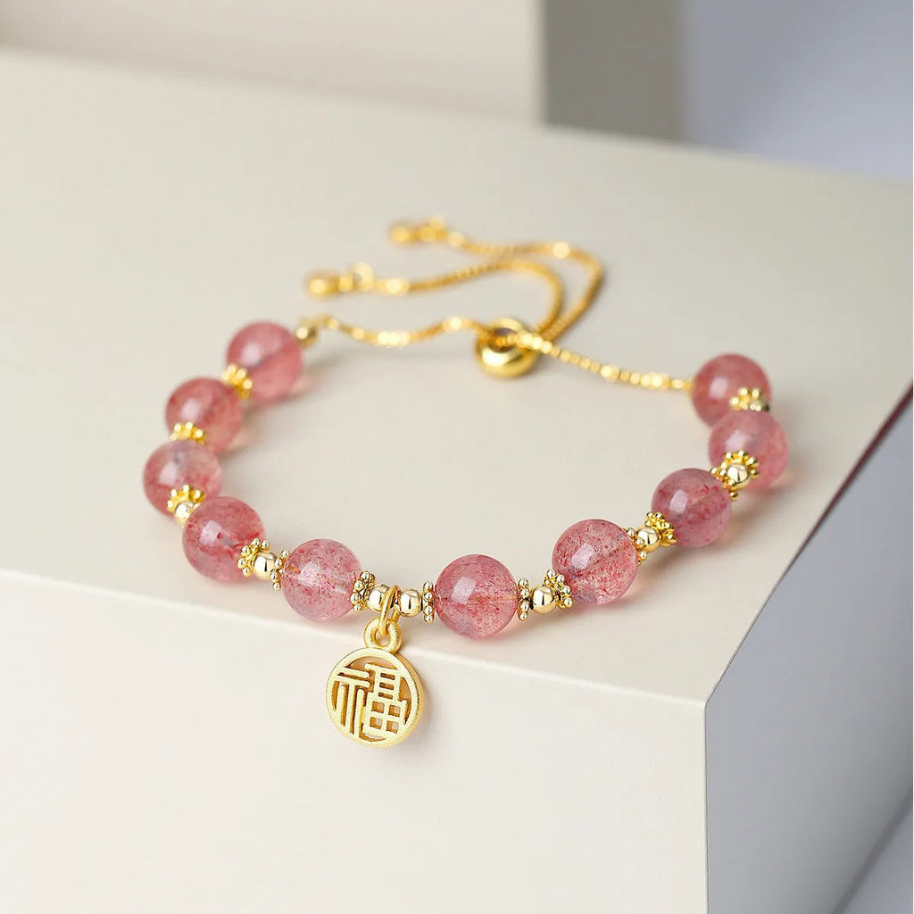 Women's Strawberry Quartz crystal bracelet with geometric design and fu character charm on wrist