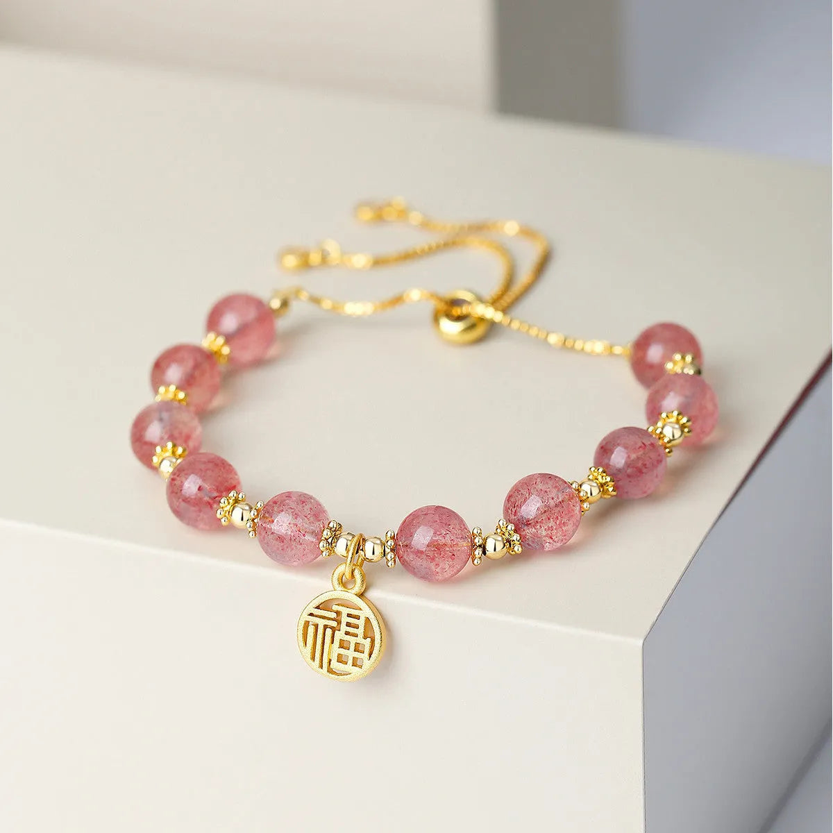 Women's Strawberry Quartz crystal bracelet with geometric design and fu character charm on wrist