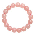 Natural pink crystal barrel bead bracelet with geometric design on a wrist.