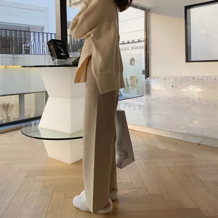 Woman wearing cream white knitted high-waist wide-leg winter trousers.