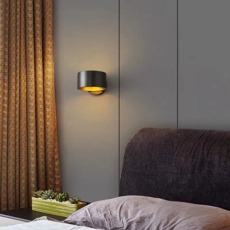 A simple modern copper wall lamp on a wall, shown in a black finish.