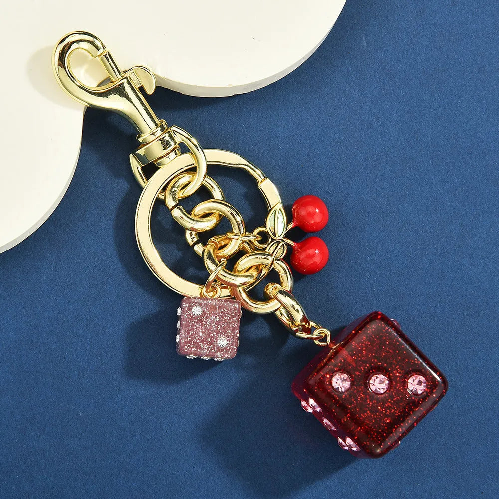 Square cherry red and silver two-tone dice keychain pendant with metal keyring on a grey background