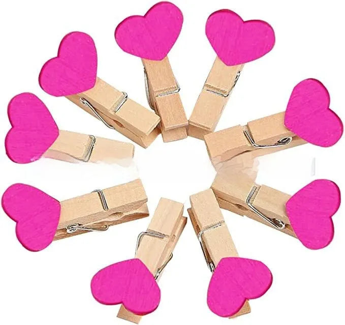 Set of five colourful handmade wooden heart-shaped clips in red, pink, white, and yellow on a wooden surface.