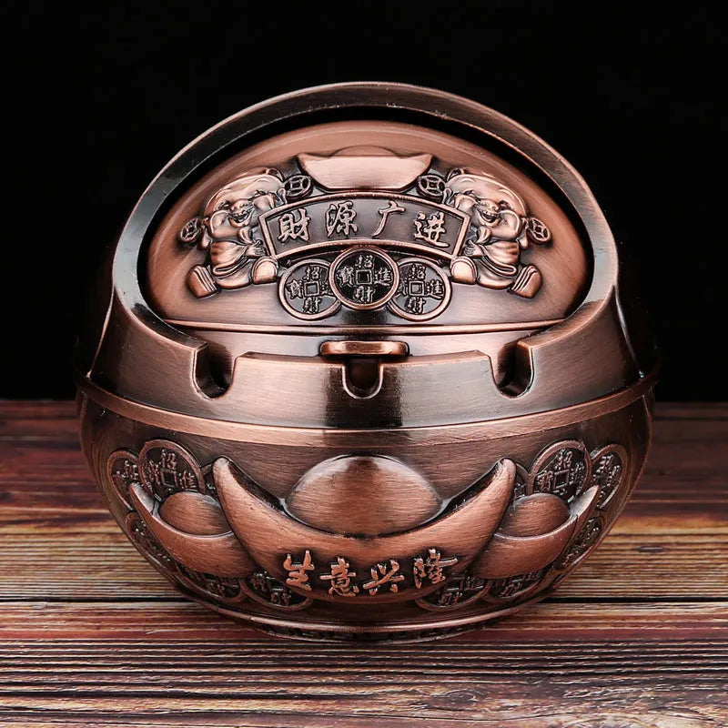 Bronze and red copper alloy decorative ashtray with smoke-extinguishing slot on a table.