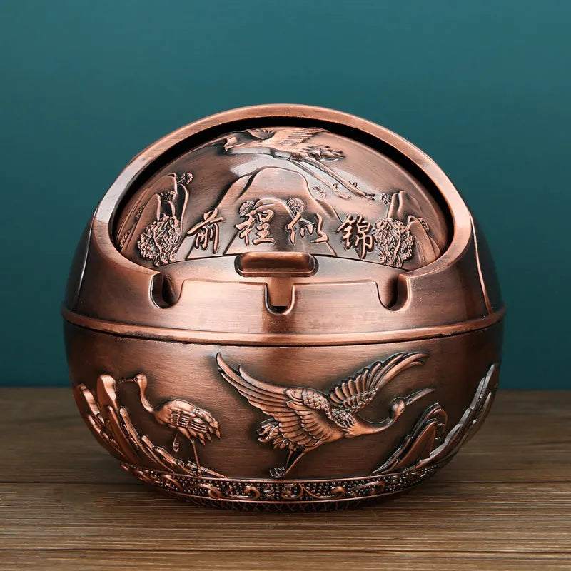Bronze and red copper alloy decorative ashtray with smoke-extinguishing slot on a table.
