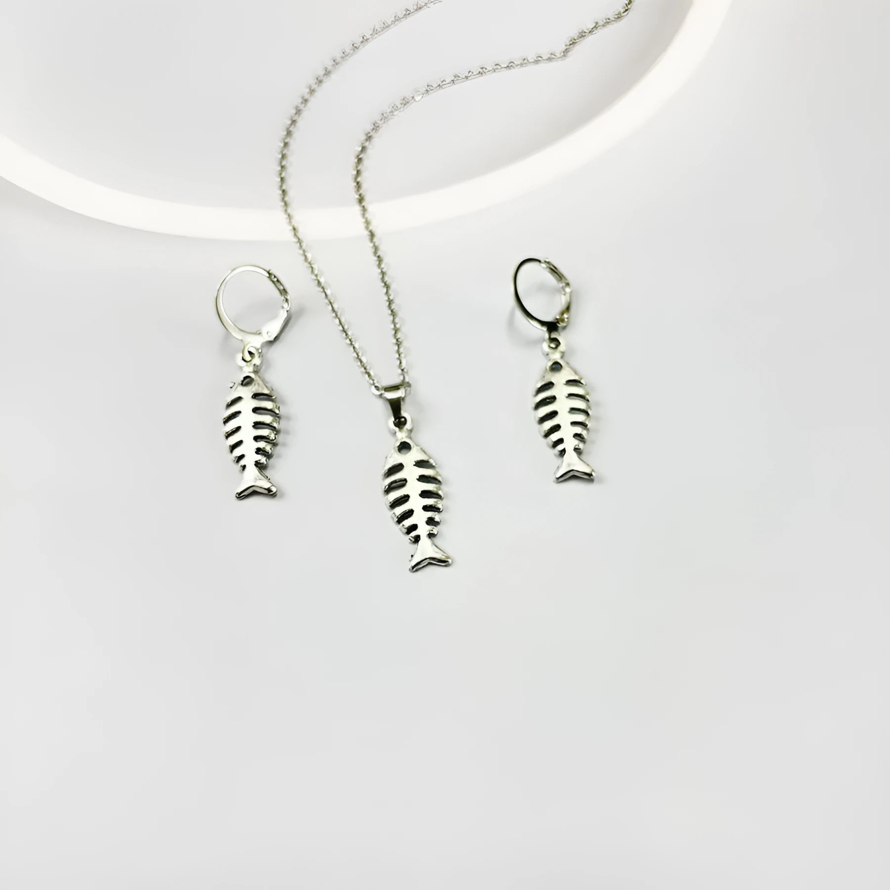 Fishbone pendant necklace and matching earrings set with adjustable chain on retro background