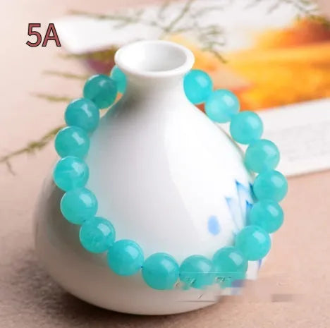 Natural blue-green Grade 7A Amazonite scattered beads in various sizes next to a finished crystal bracelet.