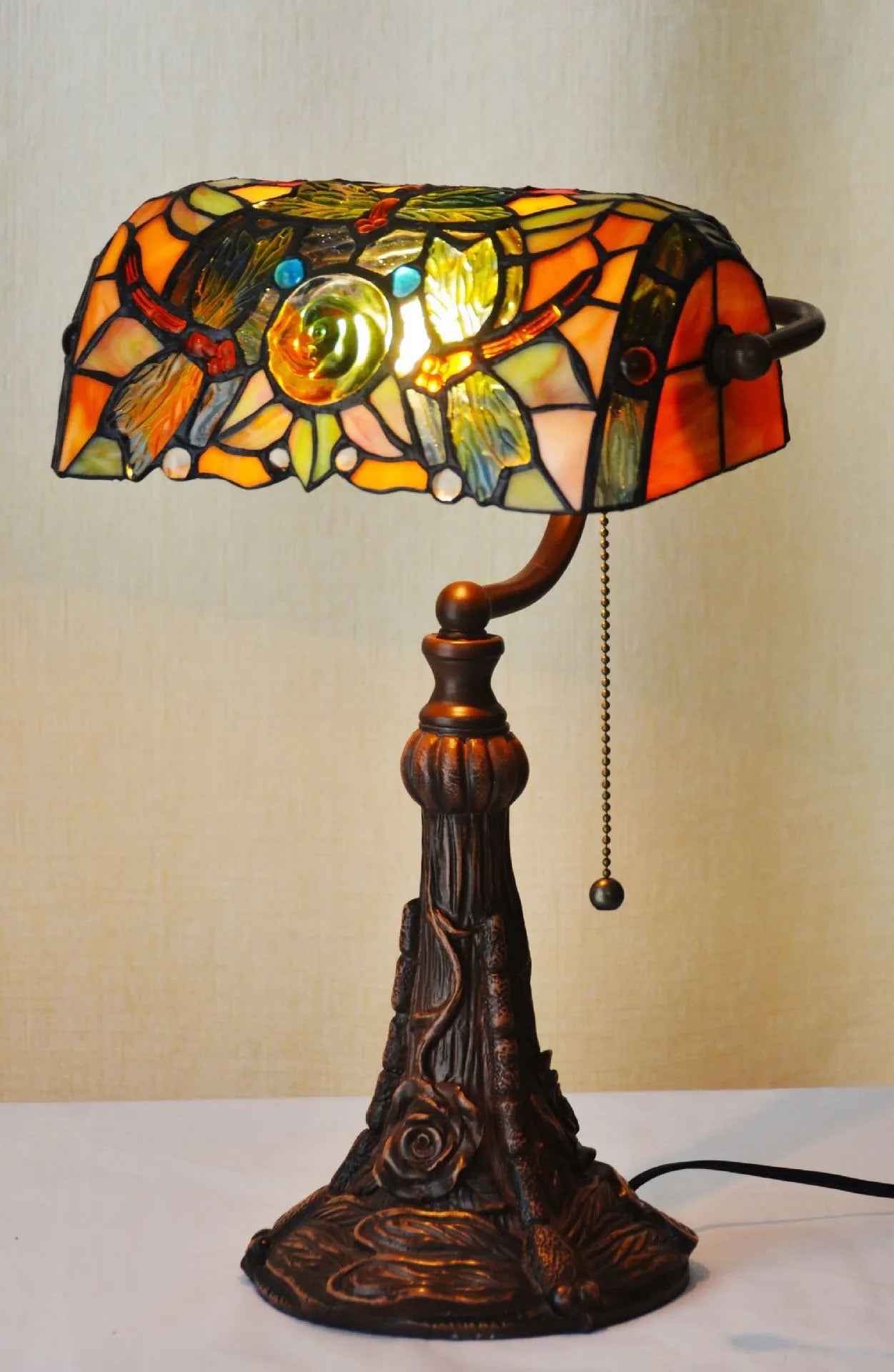 Tiffany style table lamp with colourful stained glass shade and resin base on a wooden desk