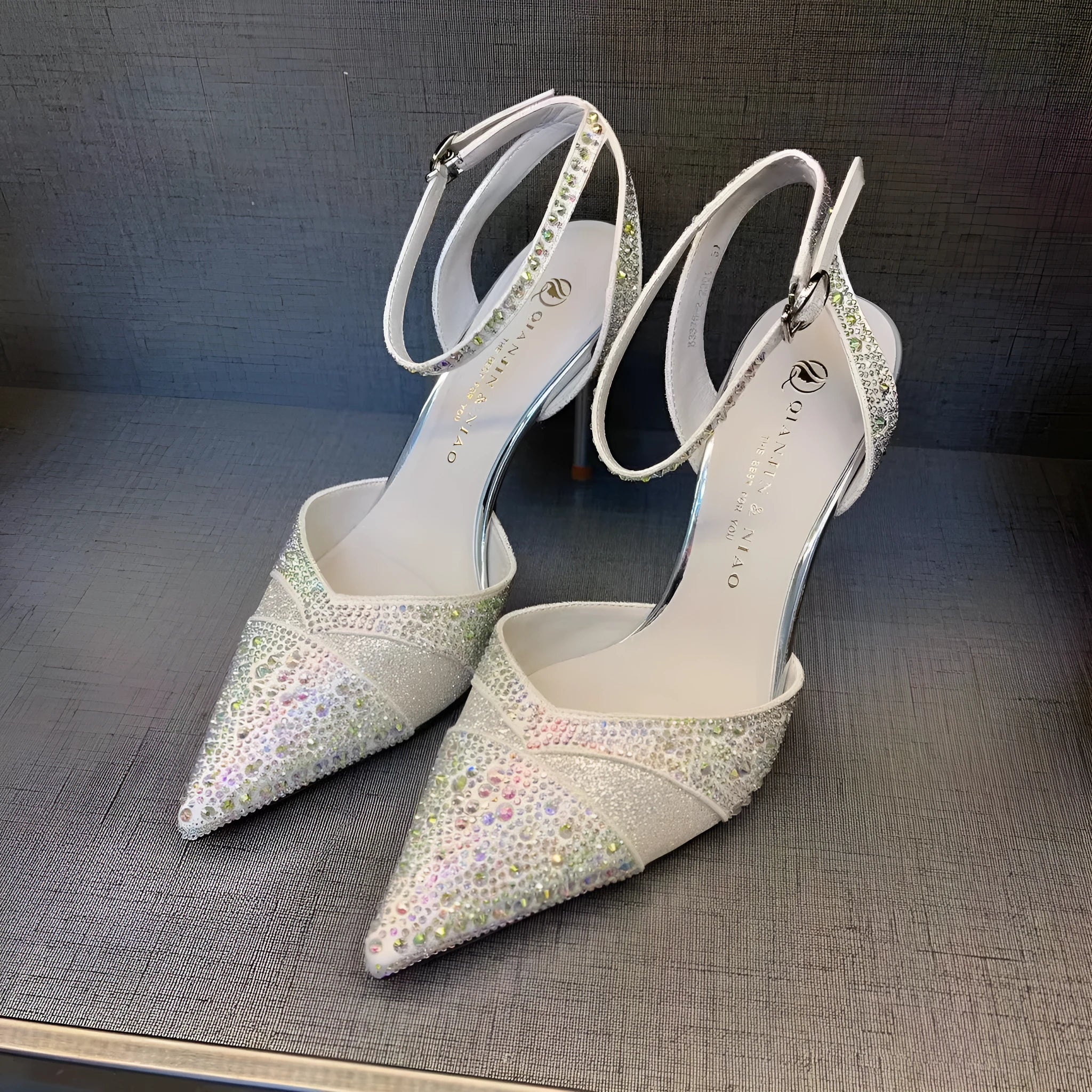 Women's silver hollow high heels with red sole and pointed stiletto heel.