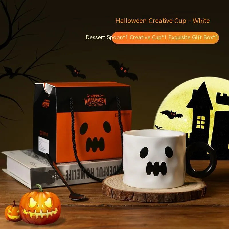 Orange ceramic Halloween pumpkin cup with handle beside dessert spoon in gift box