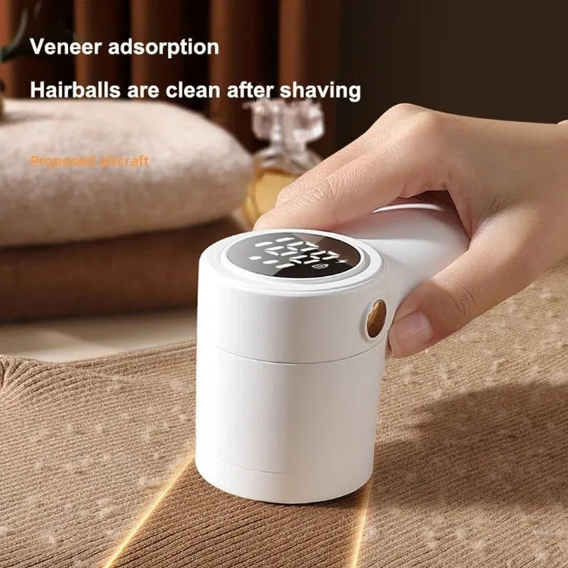 White electric lint remover with LED display showing battery level, placed beside clothing with fabric pilling