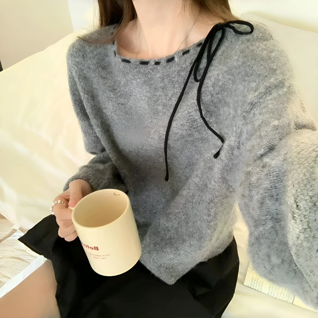A loose-fitting black women's knitted pullover on a hanger.