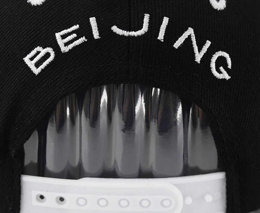 White cotton baseball cap with embroidered lettering on the front, showing the adjustable strap at the back.