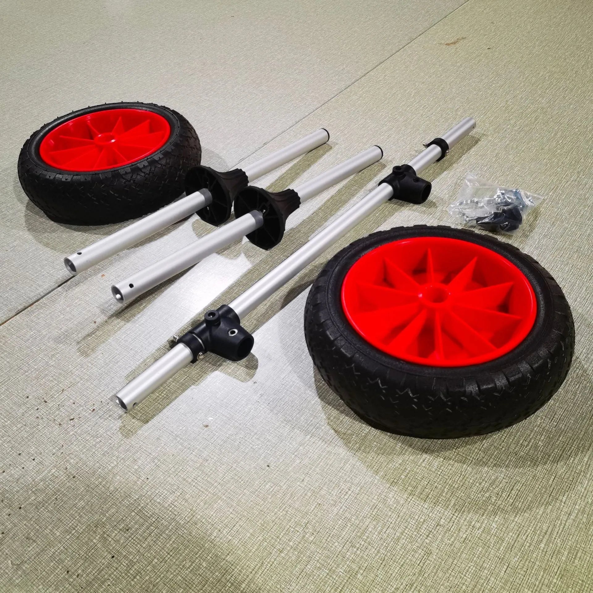 Foldable aluminium kayak handcart with rubber cradle, shown carrying an open kayak on a beach.
