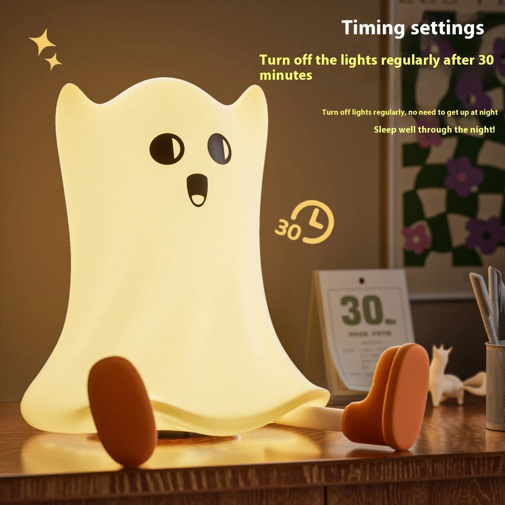 Ghost shaped silicone bedside lamp with touch control emitting soft yellow glow on a bedside table