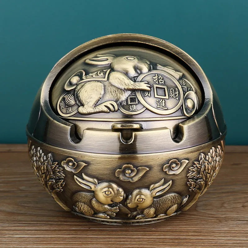 Bronze and red copper alloy decorative ashtray with smoke-extinguishing slot on a table.