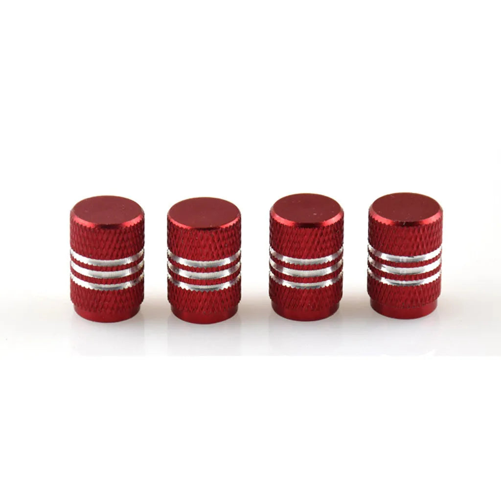 Set of coloured aluminium alloy tyre valve caps for car wheels on a grey background.