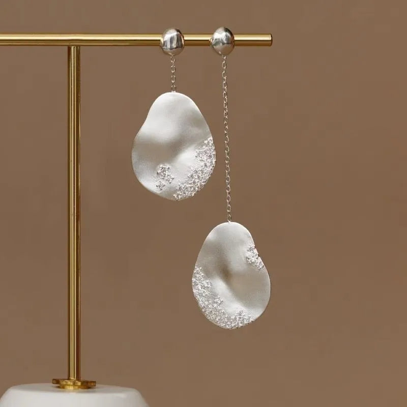 Asymmetric floral earrings with zircon stones in gold or silver finish.