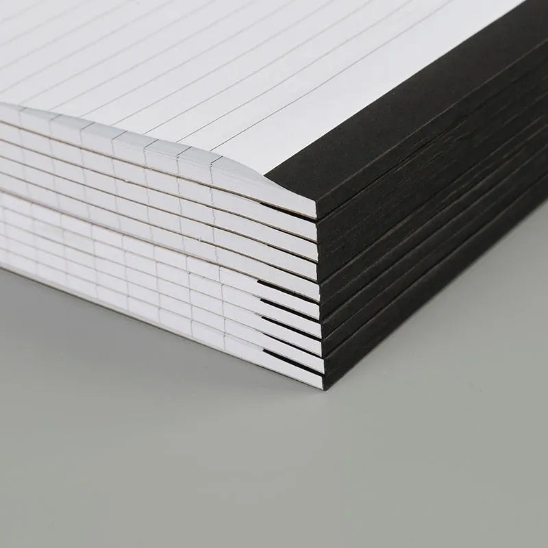 A4 tearable grid notebook with a paper cover, lying open to show ivory pages and wireless binding.