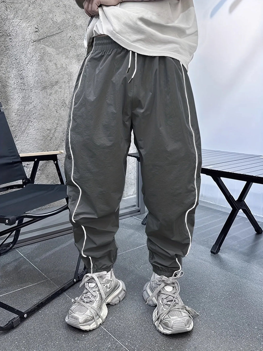 Man wearing loose-fit cropped sports trousers in bamboo fibre, showing army green colour and elastic waist.